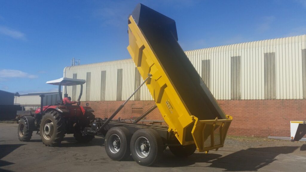 Roadking RD10 tandem axle rock dumper tipping behind a tractor